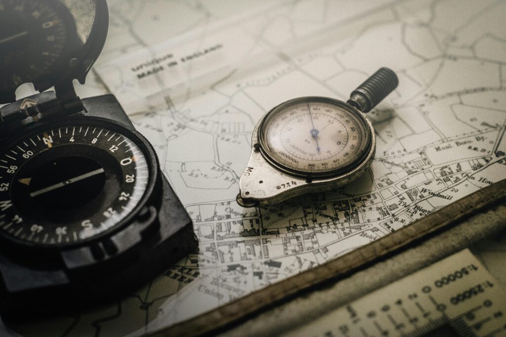 A vintage compass and navigation instrument on an old map, showcasing precision tools for exploration.