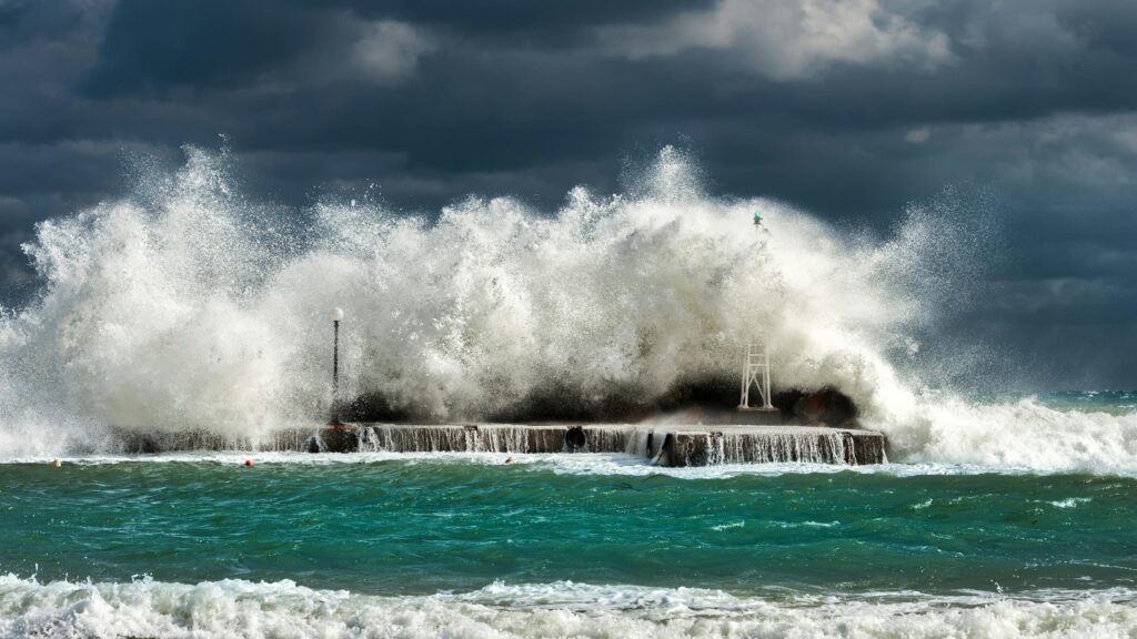 Dramatic ocean waves crashing against a concrete structure in Pantanassa, capturing nature's raw power.